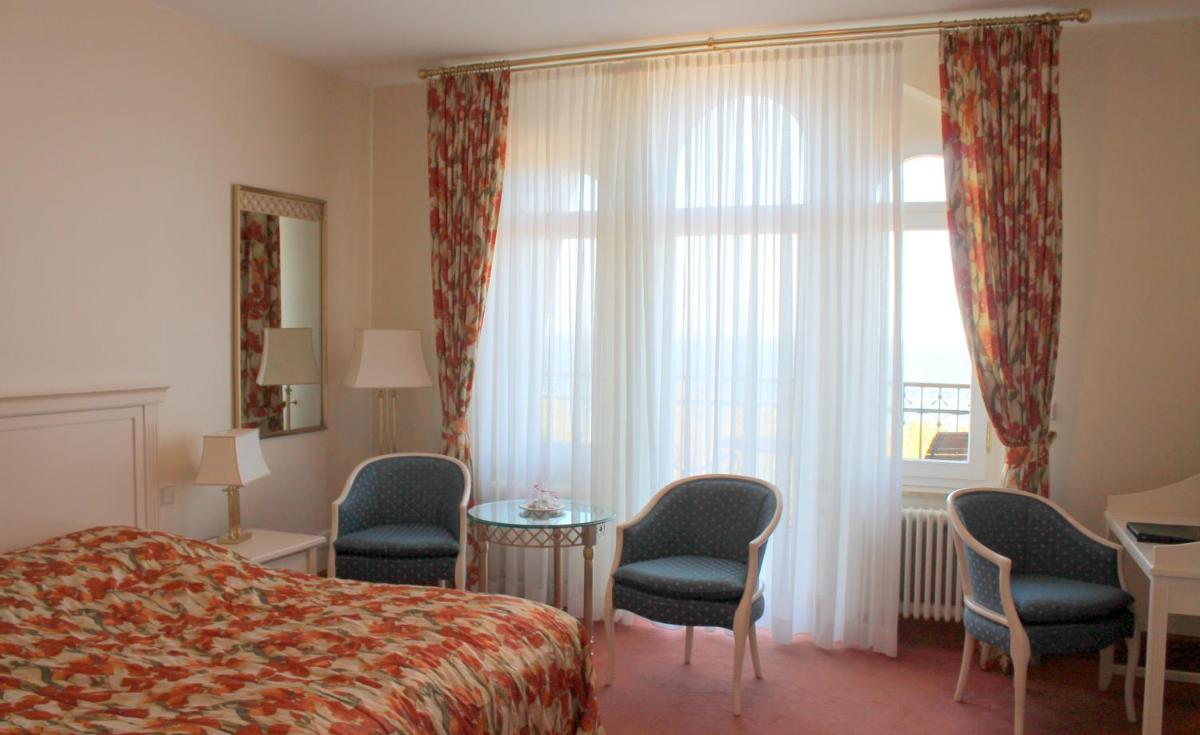 ein Hotelzimmer mit einem Bett und Stühlen und einem Fenster in der Unterkunft Usedom Palace in Zinnowitz