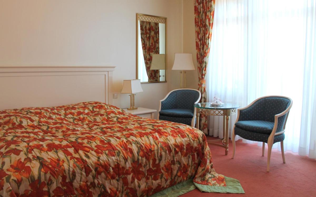 ein Hotelzimmer mit einem Bett und zwei Stühlen in der Unterkunft Usedom Palace in Zinnowitz + 37 Fotos
