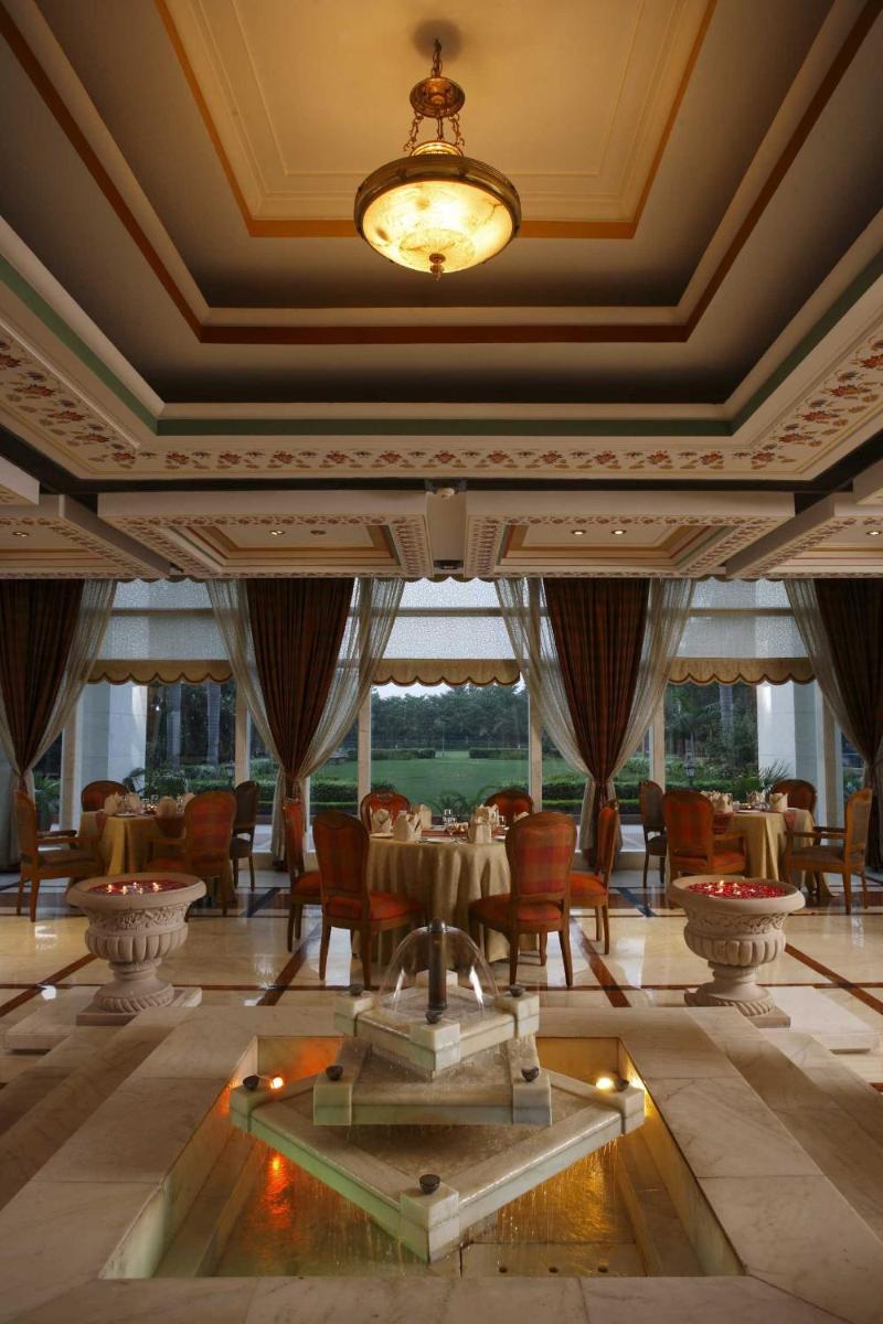 a dining room with tables and chairs and a chandelier at Jaypee Palace Hotel in Agra
