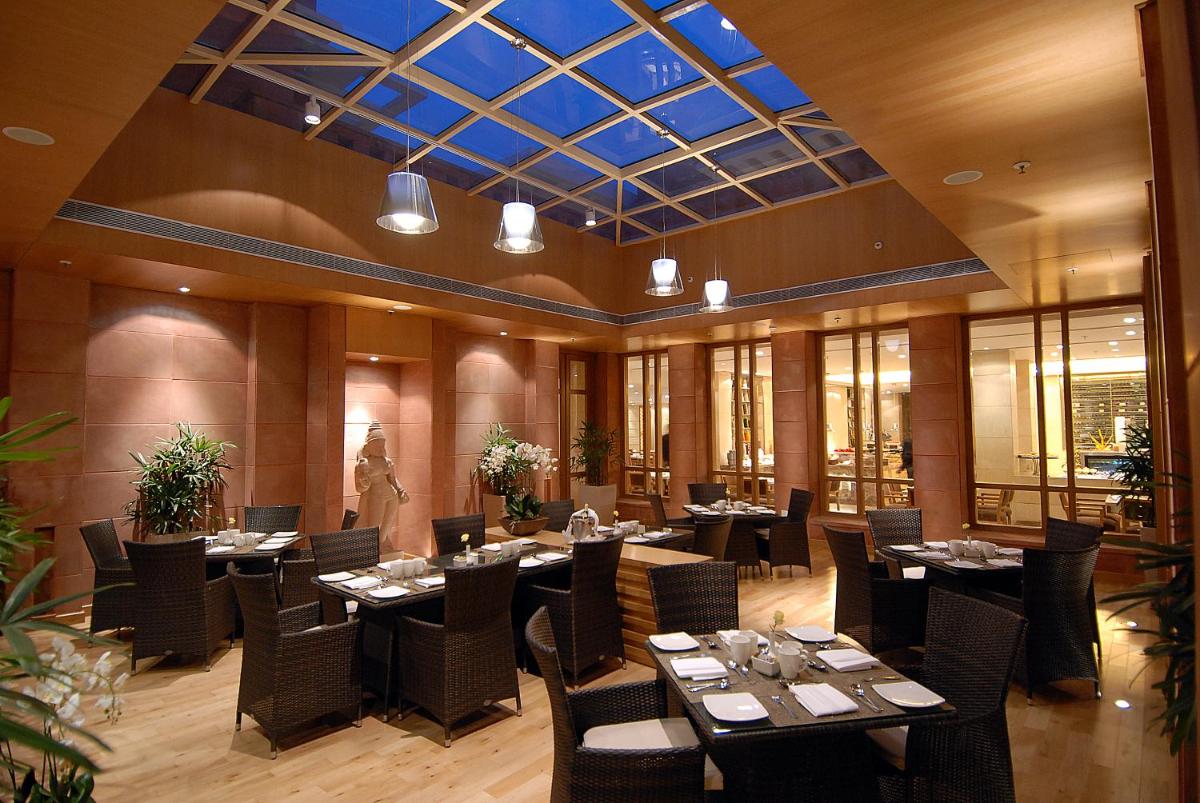 a restaurant with tables and chairs and a glass ceiling at Jaypee Palace Hotel in Agra