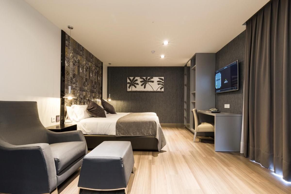 Una habitación de hotel con una cama, una silla y un televisor. en Sant Jordi Boutique Hotel, en Calella