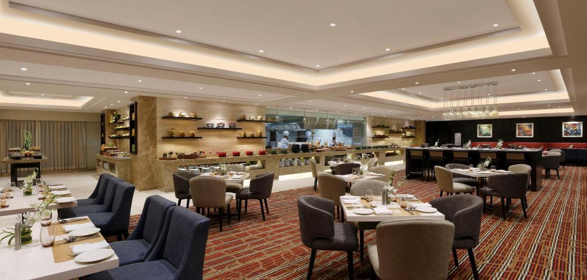 a restaurant with tables and chairs and a bar at Novotel Lucknow Gomti Nagar in Lucknow