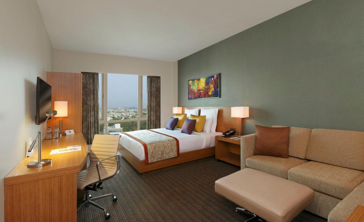 a hotel room with a bed and a couch at Novotel Lucknow Gomti Nagar in Lucknow