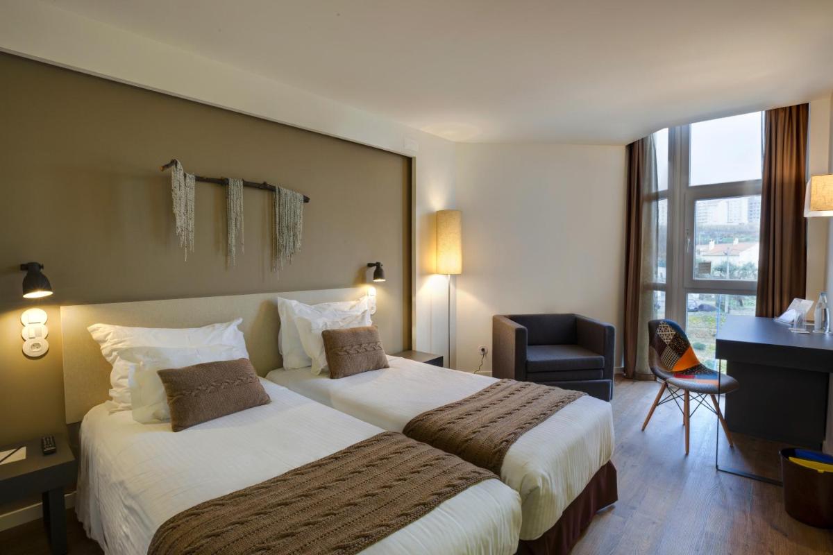 um quarto de hotel com duas camas e uma escrivaninha em Puralã - Wool Valley Hotel & SPA na Covilhã mais 109 fotografias
