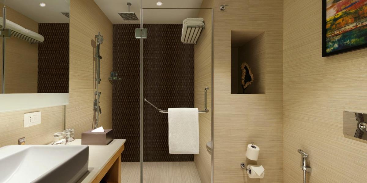 a bathroom with a shower and a sink and a shower at Novotel Lucknow Gomti Nagar in Lucknow
