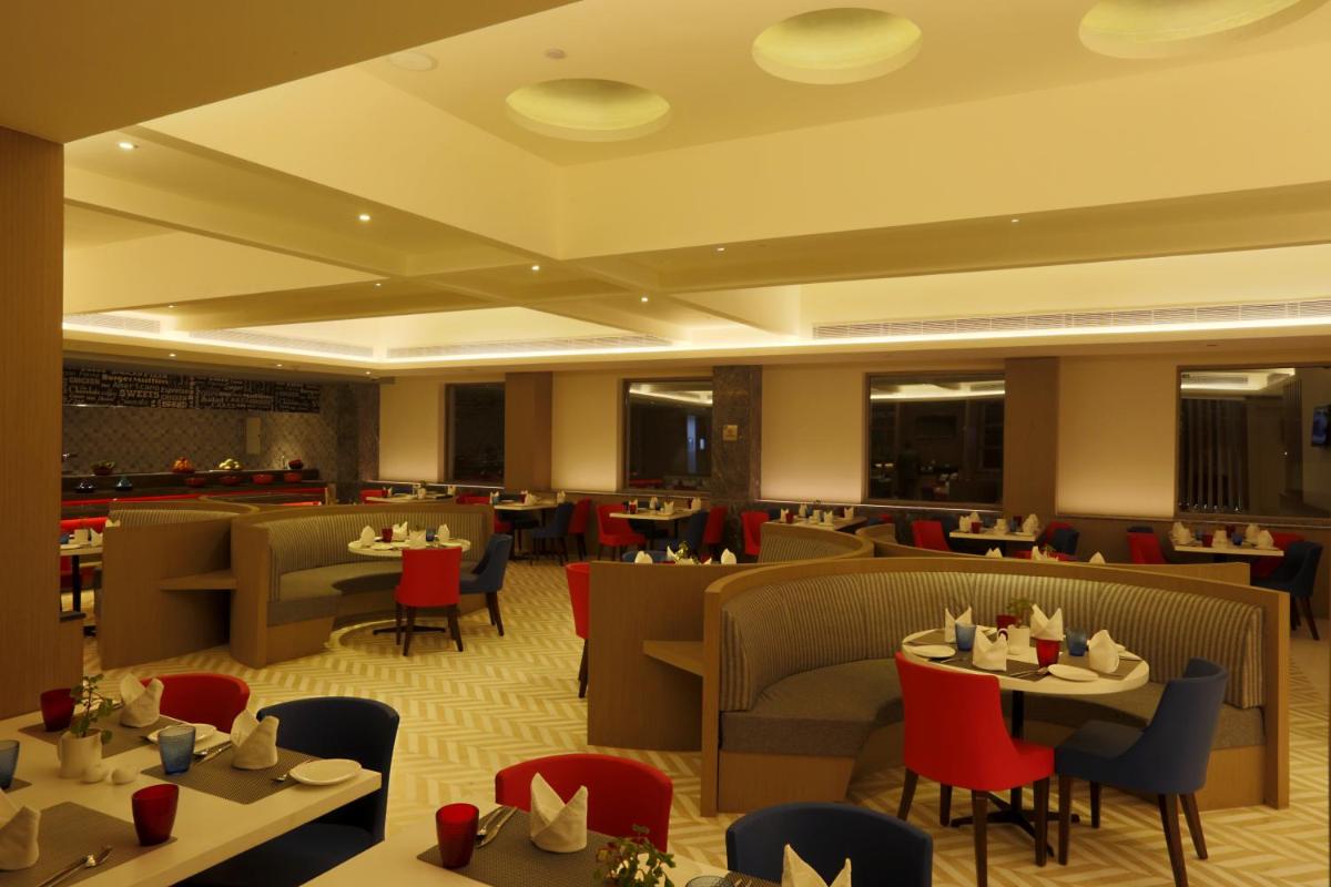 a dining room with tables and chairs and a restaurant at Ramada by Wyndham Lucknow Hotel and Convention Center in Lucknow