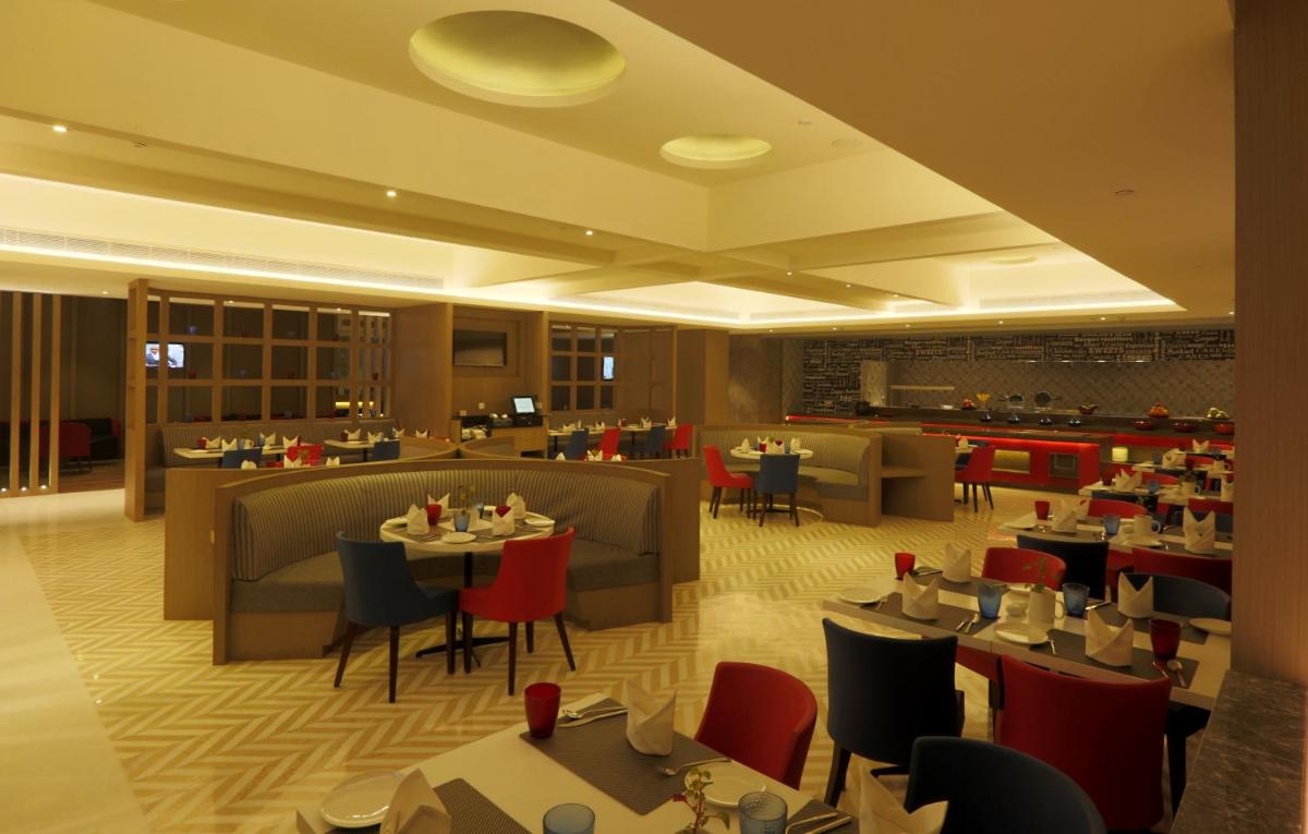 a dining room with tables and chairs in a restaurant at Ramada by Wyndham Lucknow Hotel and Convention Center in Lucknow