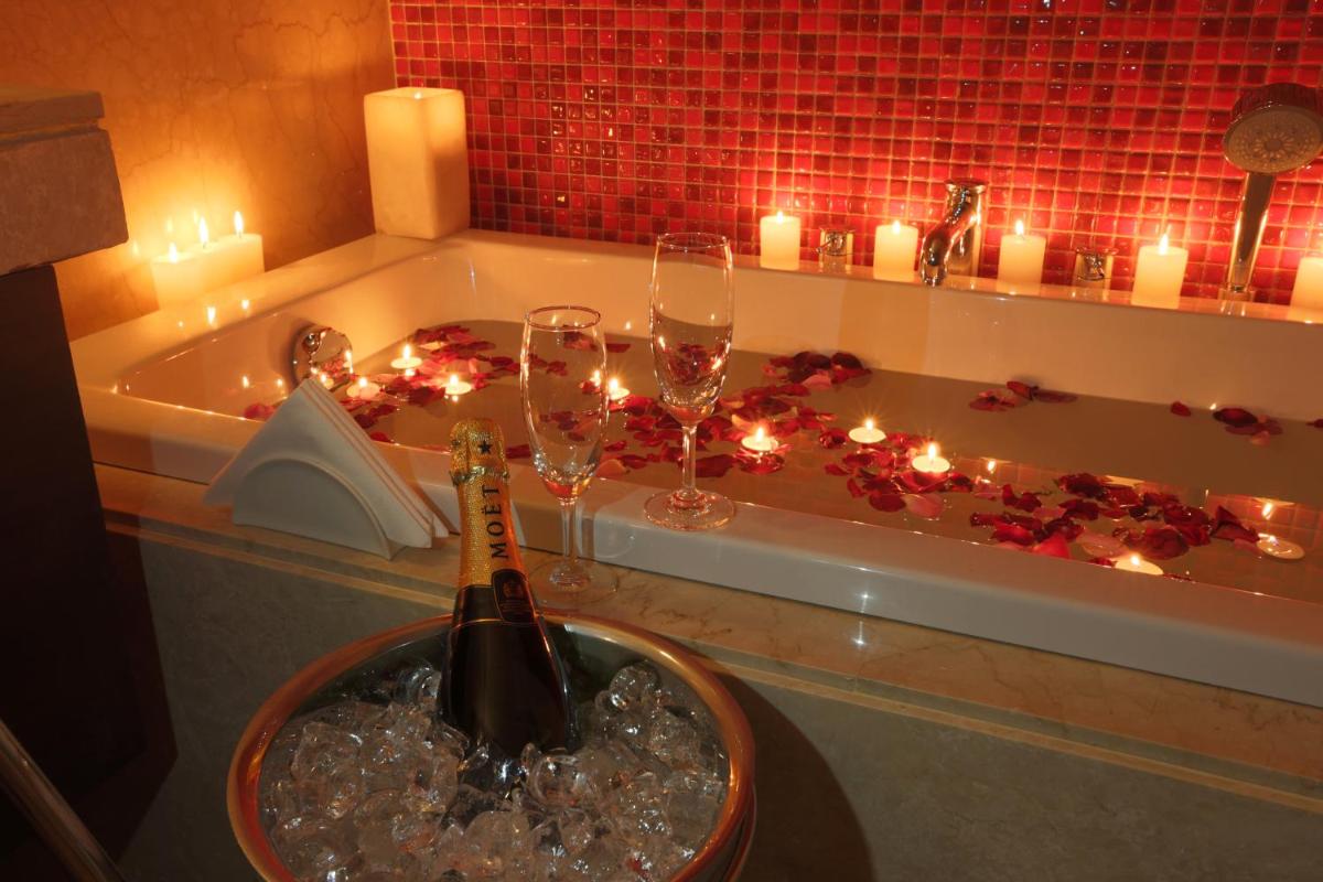 a bottle of champagne in a bath tub with candles at Ramada by Wyndham Lucknow Hotel and Convention Center in Lucknow