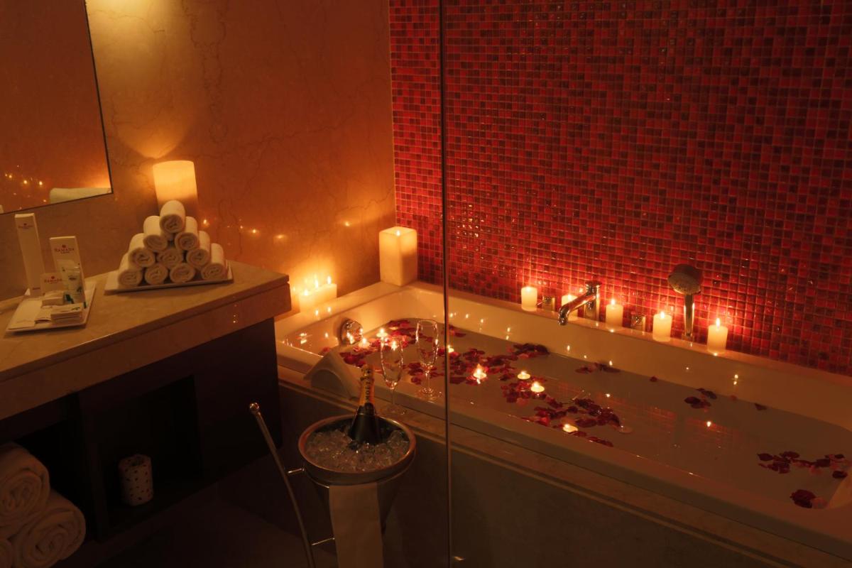 a bathroom with candles and a bath tub with a sink at Ramada by Wyndham Lucknow Hotel and Convention Center in Lucknow