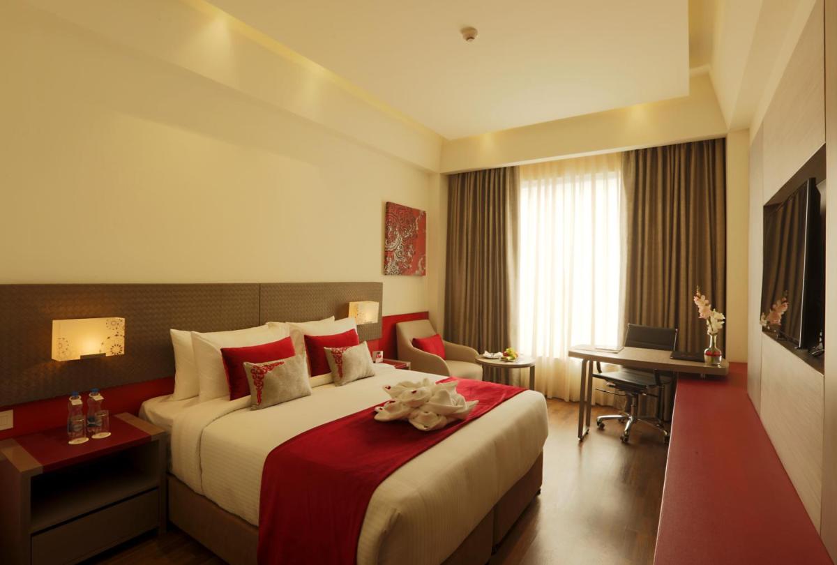 a hotel room with a large bed and a desk at Ramada by Wyndham Lucknow Hotel and Convention Center in Lucknow