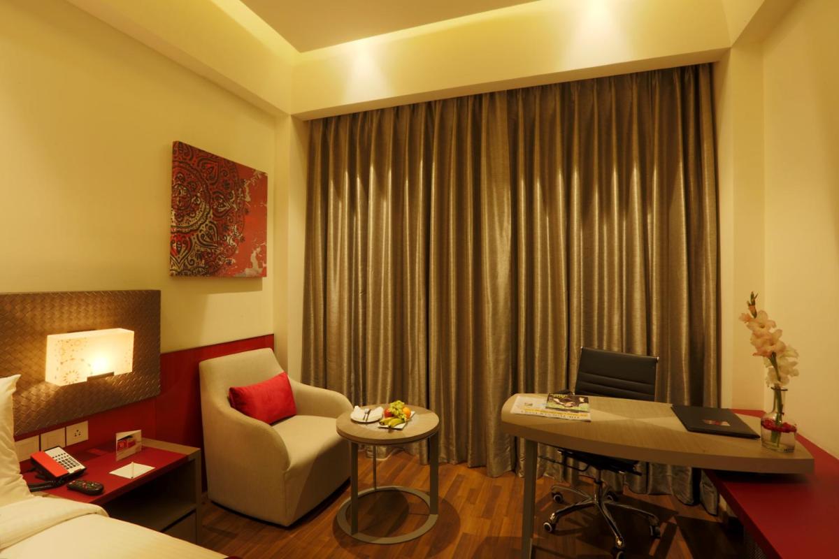 a hotel room with a bed and a desk and a chair at Ramada by Wyndham Lucknow Hotel and Convention Center in Lucknow