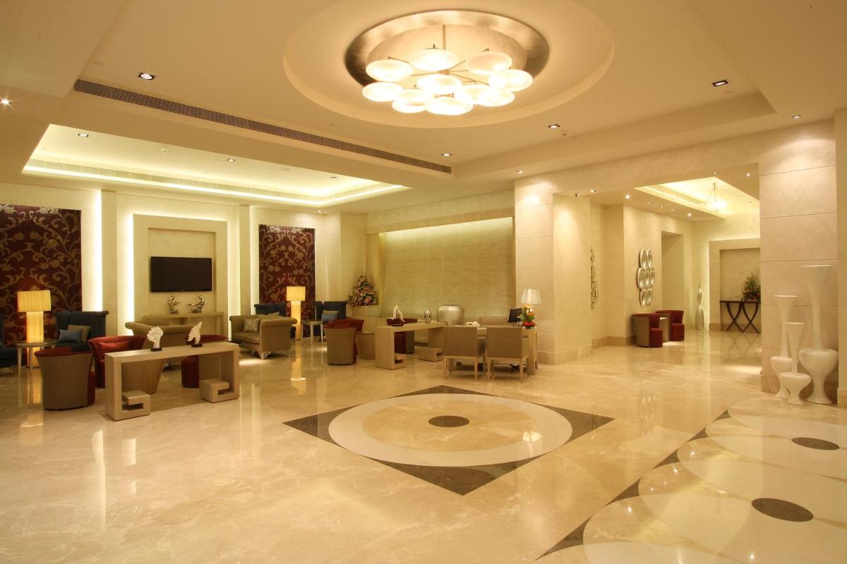 a lobby with a waiting area with tables and chairs at Radisson Hyderabad Hitec City in Hyderabad