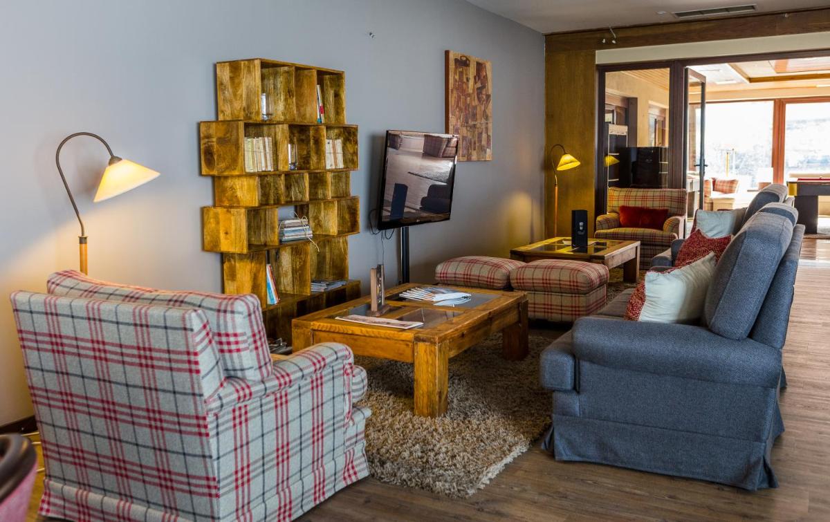 uma sala de estar com duas cadeiras e uma tv em Puralã - Wool Valley Hotel & SPA na Covilhã