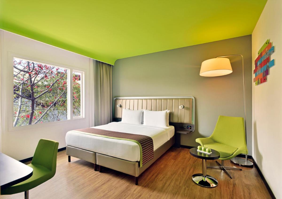 a bedroom with a bed and two green chairs at Park Inn by Radisson,South Delhi in New Delhi a bedroom with a bed and two green chairs at Park Inn by Radisson,South Delhi in New Delhi