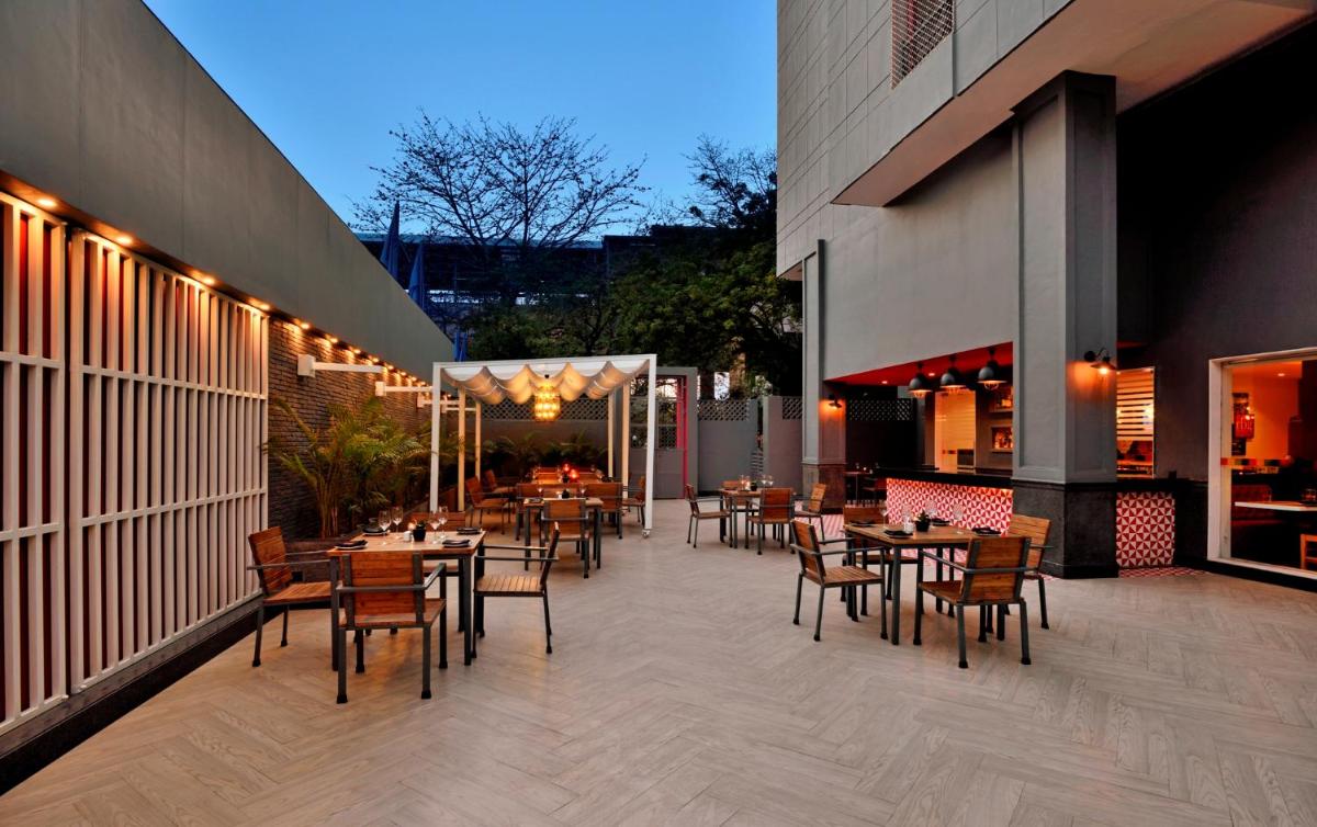 a restaurant with tables and chairs on a patio at Park Inn by Radisson,South Delhi in New Delhi a restaurant with tables and chairs on a patio at Park Inn by Radisson,South Delhi in New Delhi