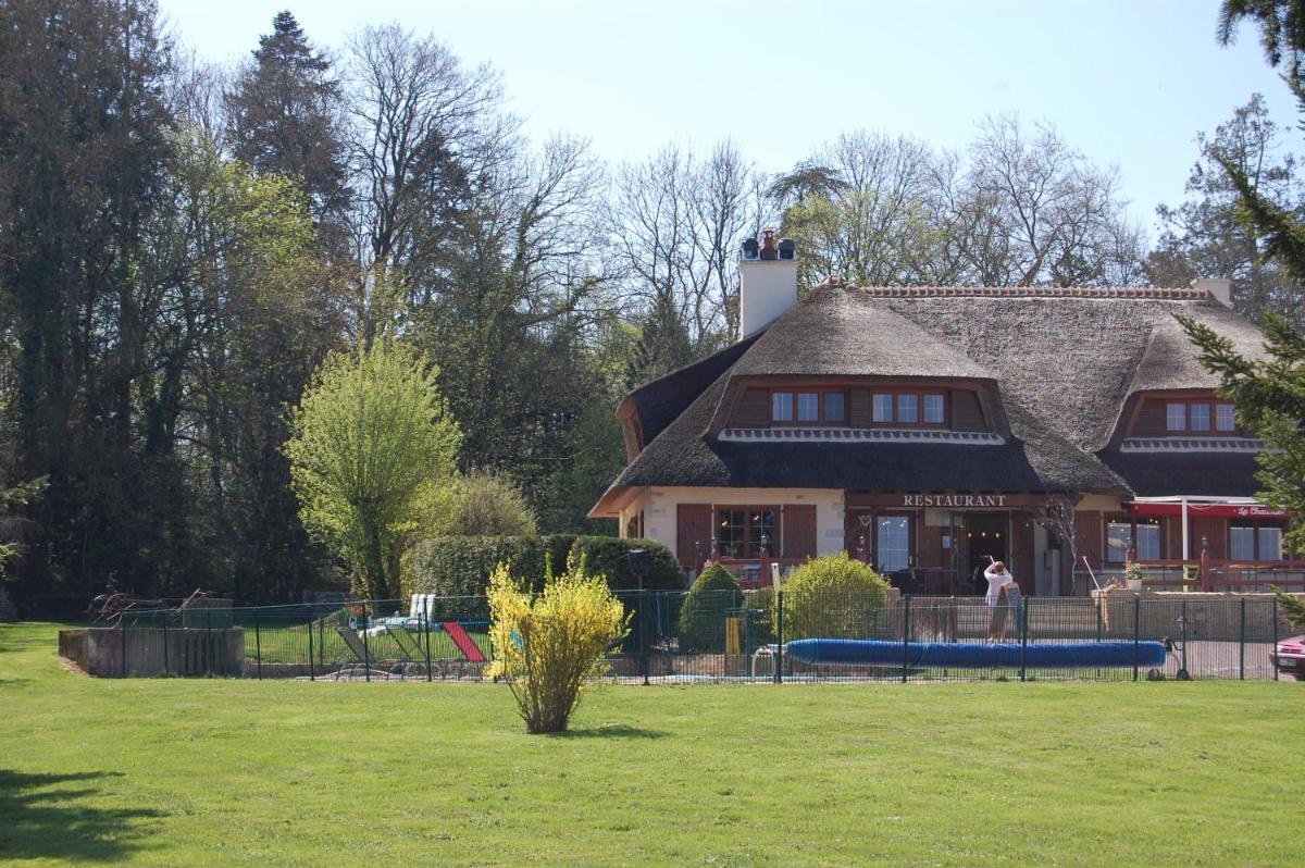 une grande maison avec une aire de jeux dans un parc dans l'établissement Logis Relais Saint Michel, à Saint-Michel