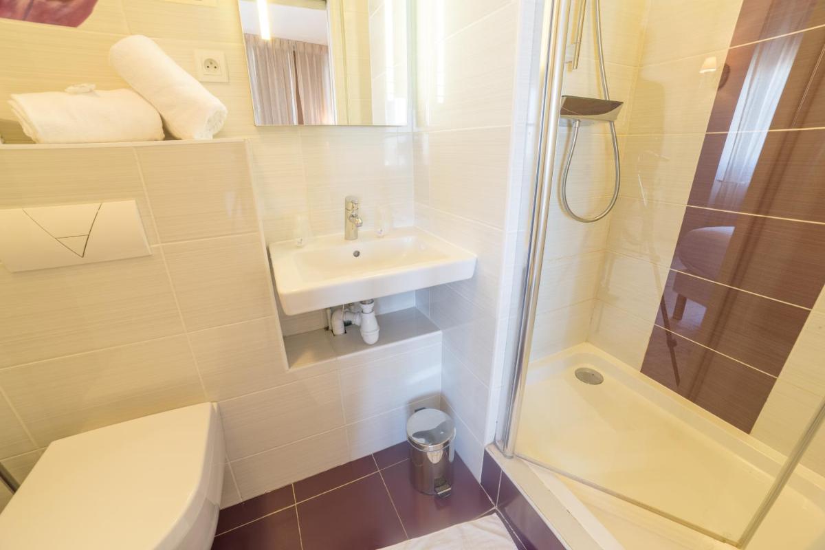 une salle de bains avec lavabo, toilettes et douche dans l'établissement The Originals Boutique, Hôtel Les Poèmes de Chartres, à Chartres