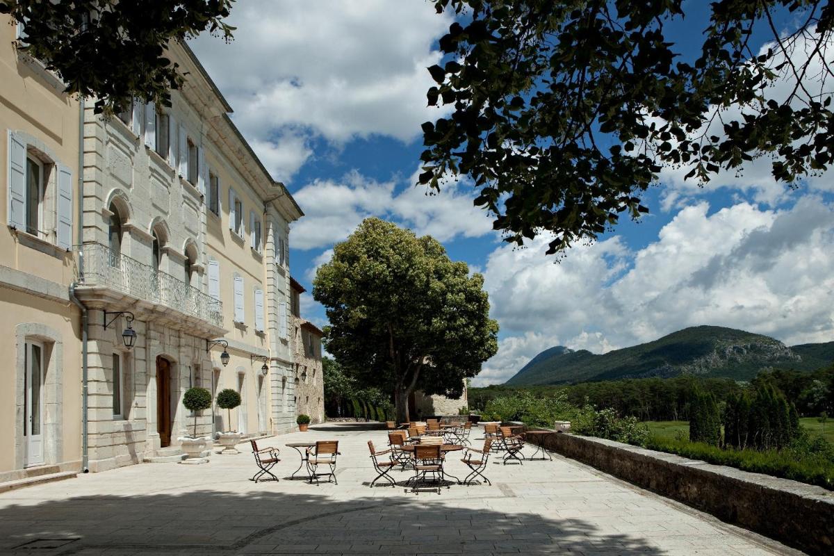 un groupe de tables et de chaises à côté d'un bâtiment dans l'établissement Château et Golf De Taulane, à La Martre