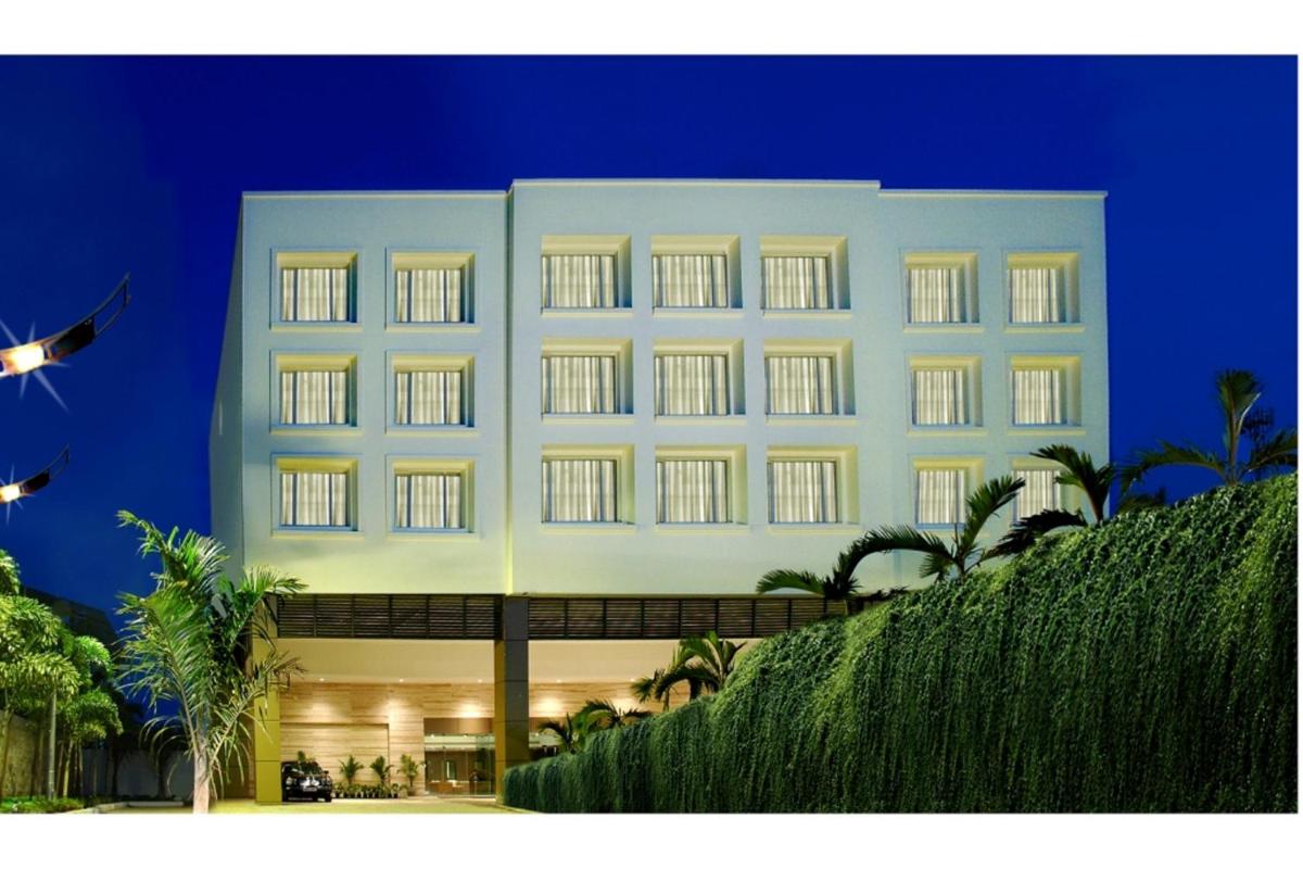 a large white building with palm trees in front of it at Park Plaza Chennai OMR in Chennai
