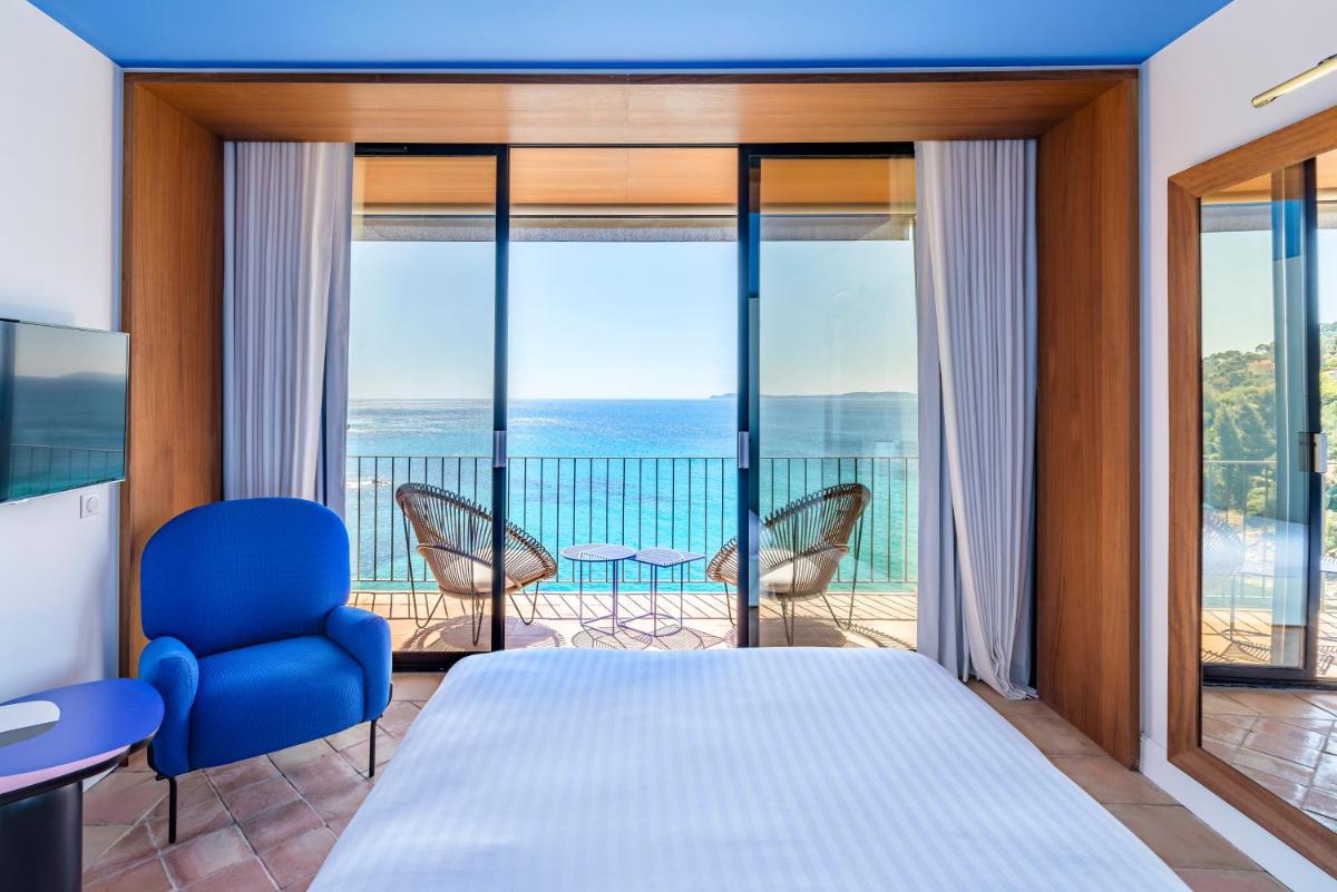 une chambre avec un lit et une vue sur l'océan dans l'établissement Hôtel Le Bailli De Suffren, à Rayol-Canadel-sur-Mer