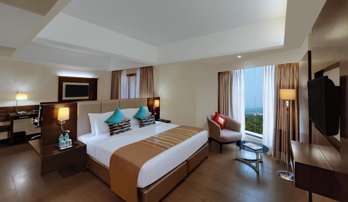 a hotel room with a large bed and a desk at The Fern Kadamba Hotel And Spa in Old Goa