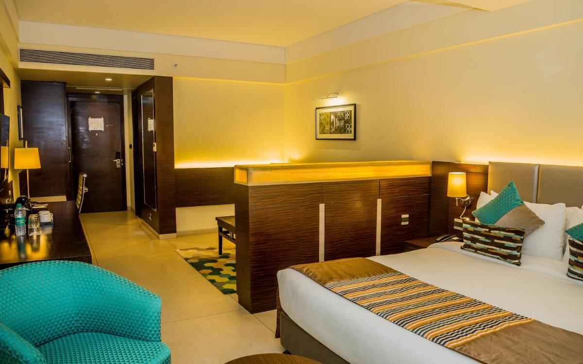 a hotel room with a bed and a chair at The Fern Kadamba Hotel And Spa in Old Goa