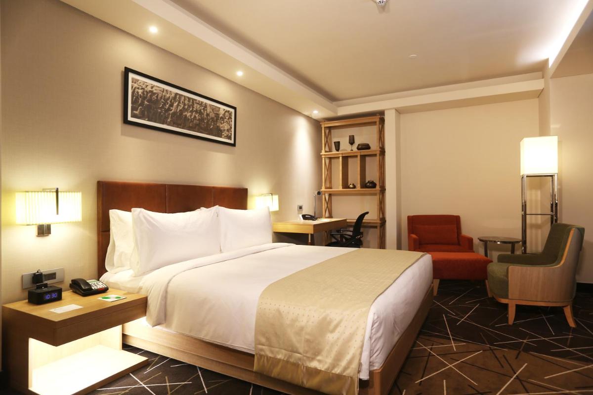 a hotel room with a bed and a chair at Holiday Inn Chennai OMR IT Expressway by IHG in Chennai