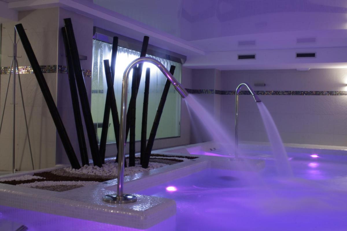 Un baño con bañera con luces moradas. en Hotel Playamar Spa, en Laredo