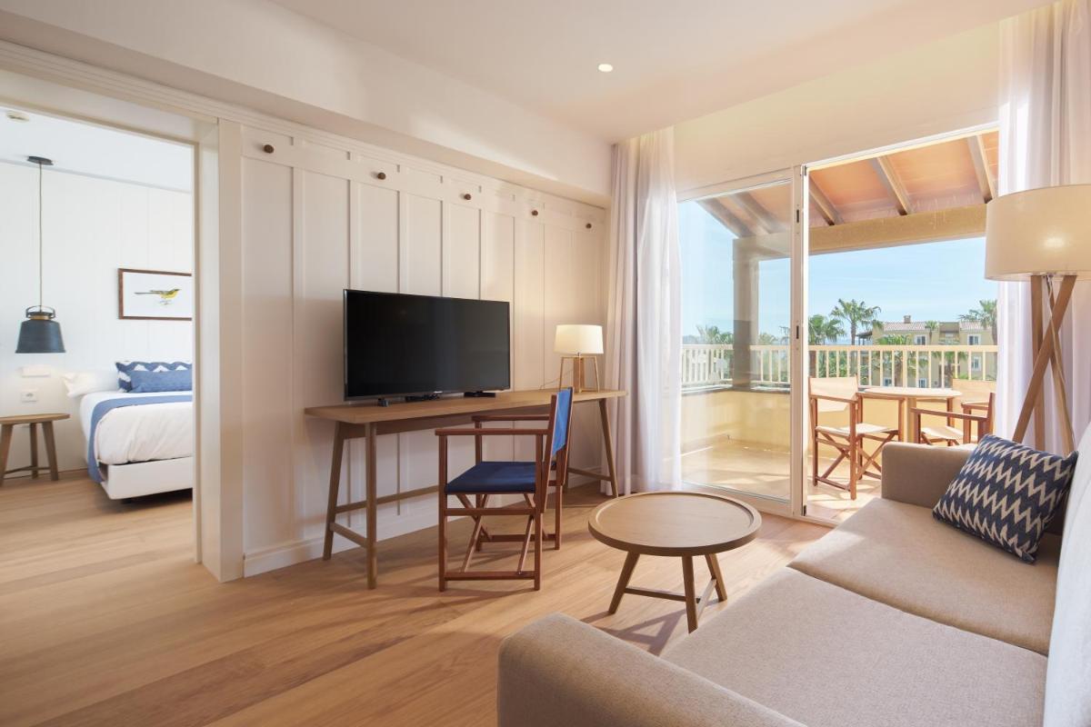 Una sala de estar con un sofá y una mesa con televisión. en Club del Sol Aparthotel, en Puerto Pollensa