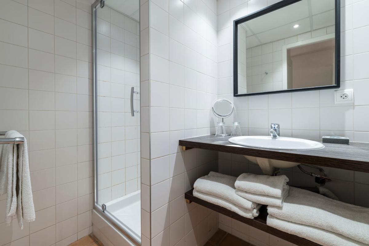 une salle de bain blanche avec un lavabo et un miroir dans l'établissement La Résidence du Bailli, à Rayol-Canadel-sur-Mer