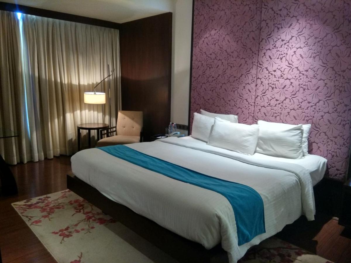 a bedroom with a large bed with a purple wall at Hotel Royal Orchid Jaipur, Tonk Road in Jaipur