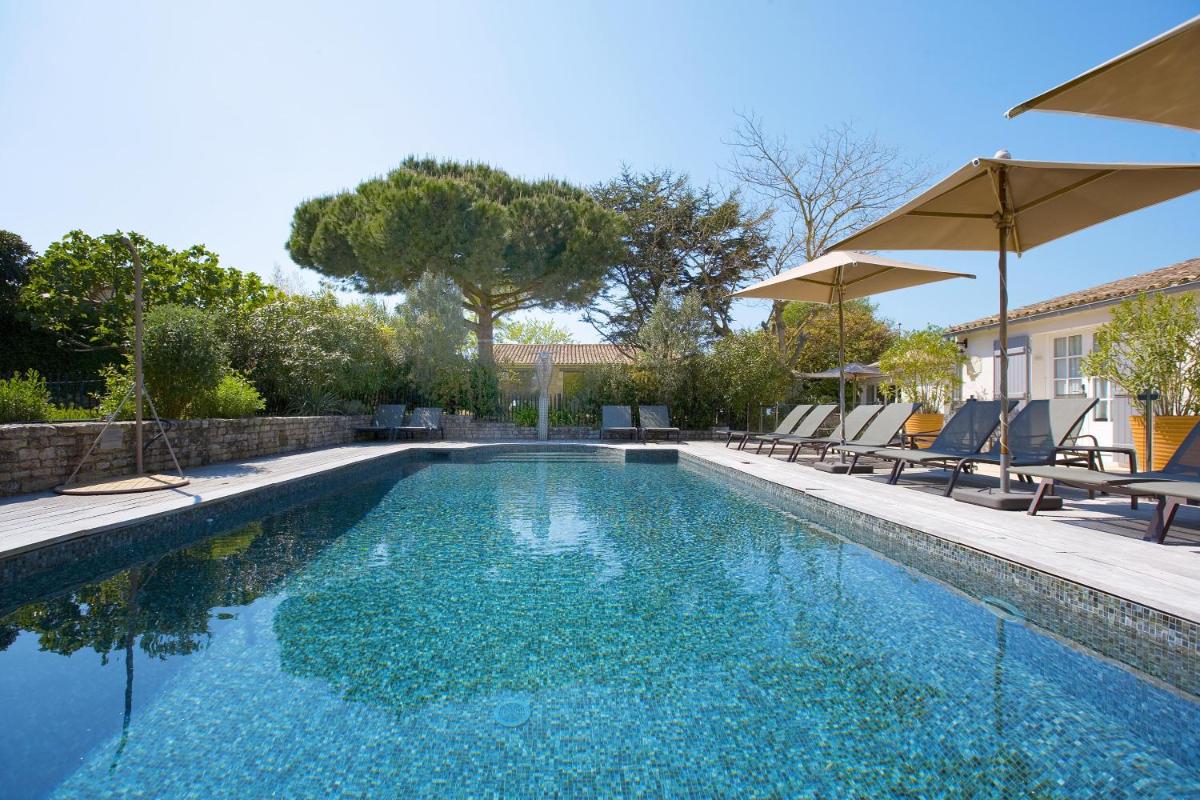 une piscine avec chaises et parasols dans l'établissement Le Clos Saint-Martin Hôtel & Spa, à Saint-Martin-de-Ré