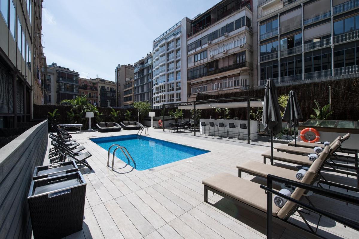 una piscina en un edificio con bancos y sombrillas en Catalonia Plaza Catalunya, en Barcelona