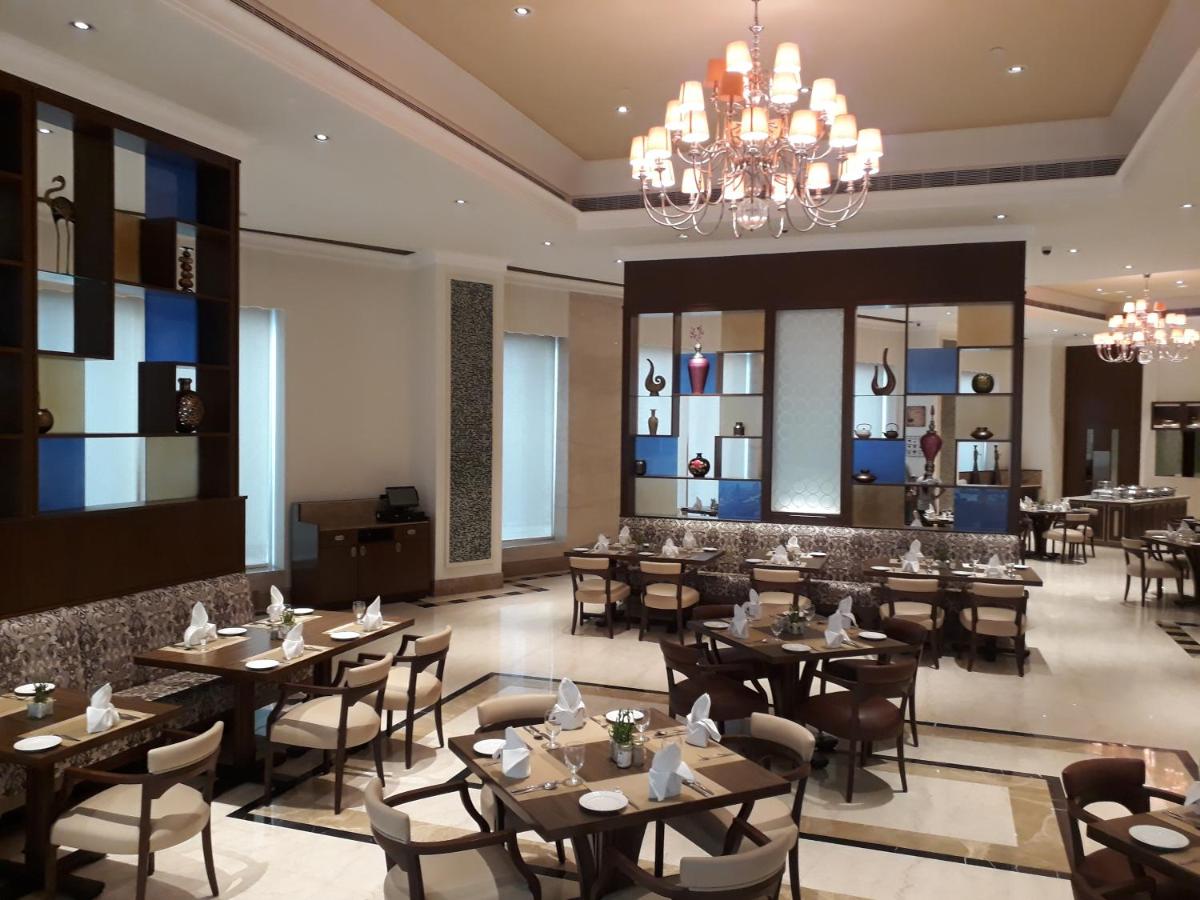 a restaurant with tables and chairs and a chandelier at Ramada Plaza Chennai in Chennai