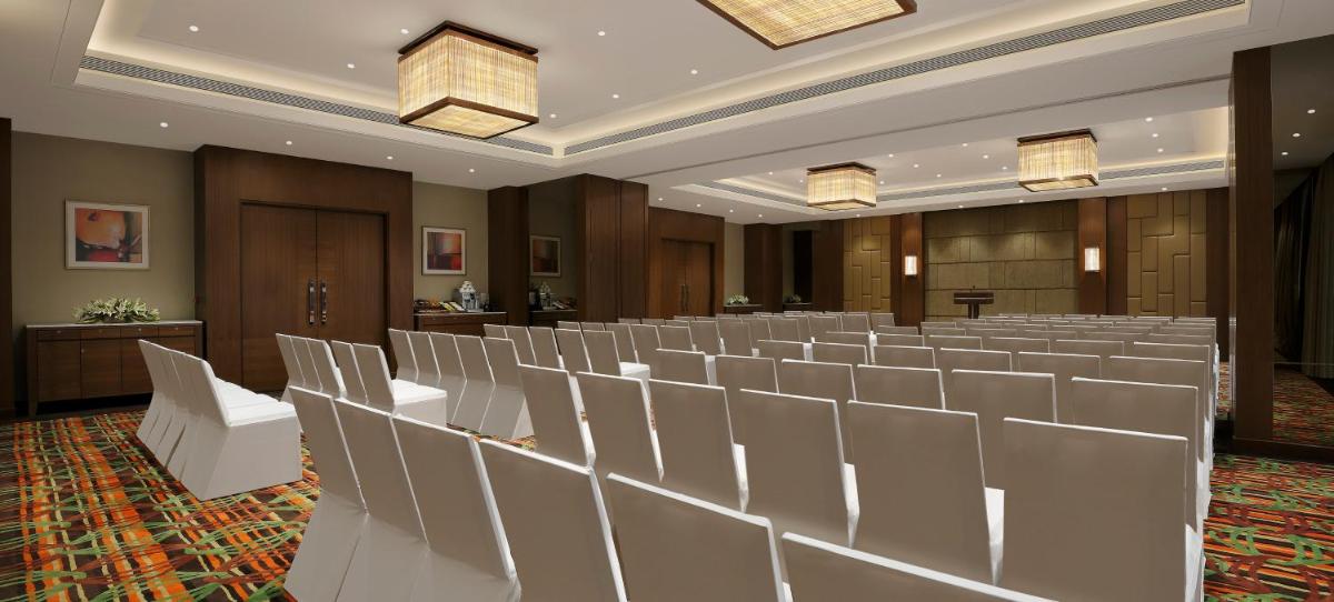 a conference room with white chairs and a podium at Novotel Lucknow Gomti Nagar in Lucknow