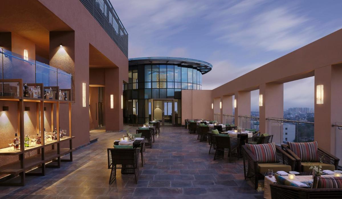 a restaurant with tables and chairs in a building at Novotel Lucknow Gomti Nagar in Lucknow