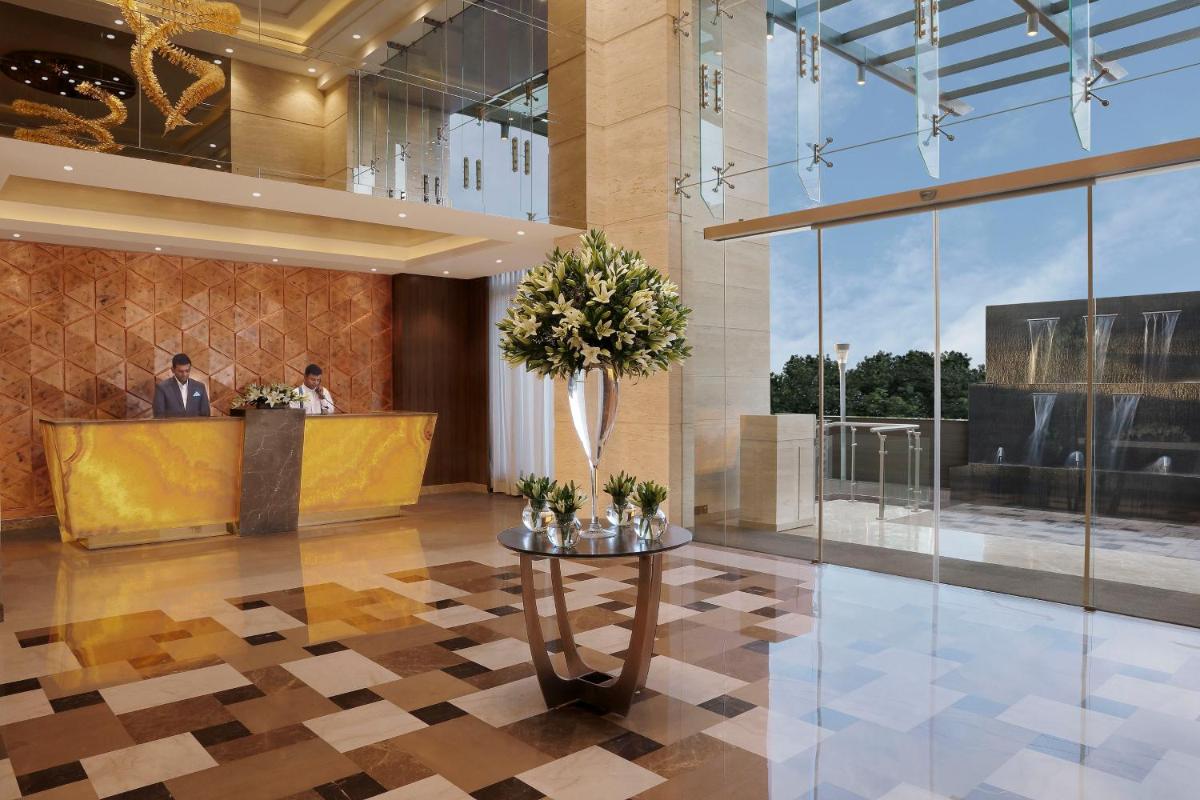 a lobby with a reception desk and a vase of flowers at Novotel Lucknow Gomti Nagar in Lucknow