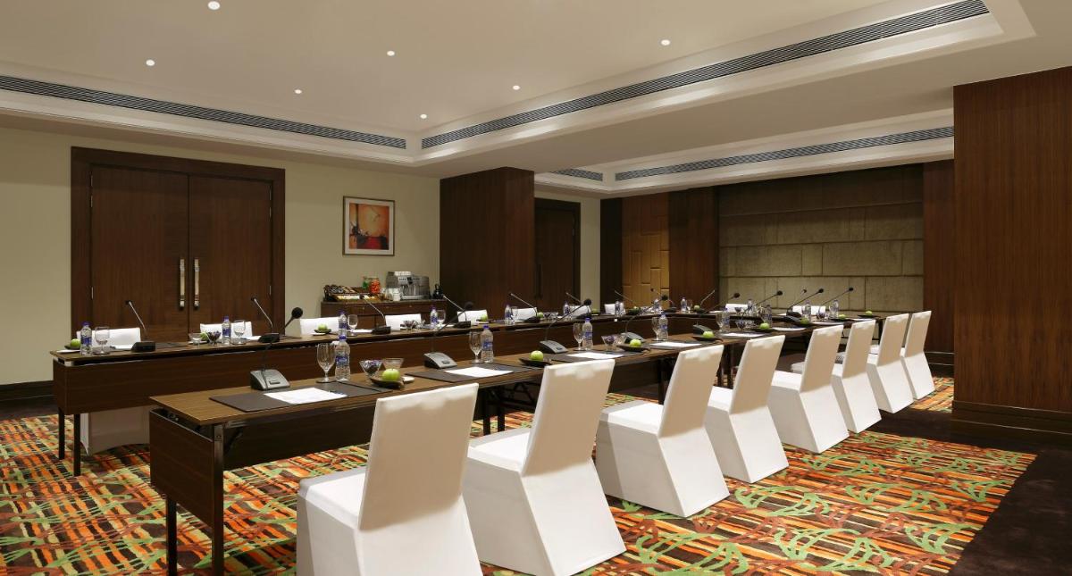 a large meeting room with a long table and white chairs at Novotel Lucknow Gomti Nagar in Lucknow