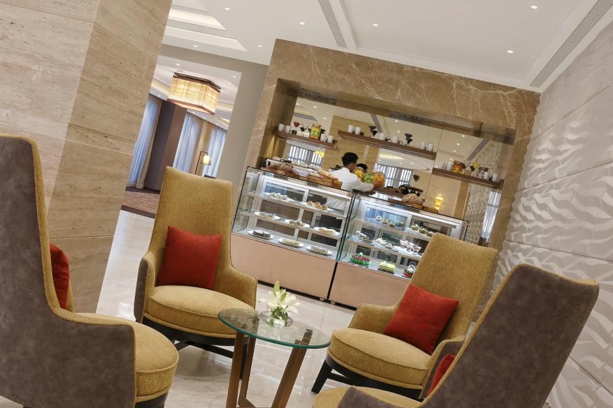 a restaurant with chairs and a counter in a room at Novotel Lucknow Gomti Nagar in Lucknow