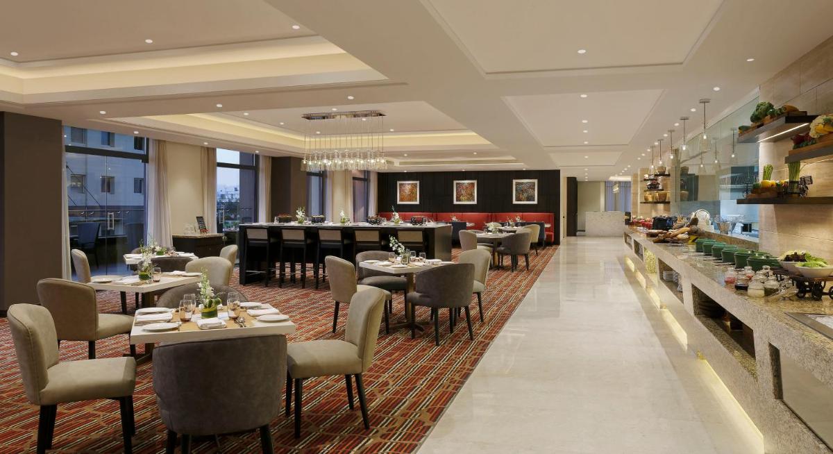 a restaurant with tables and chairs and a bar at Novotel Lucknow Gomti Nagar in Lucknow