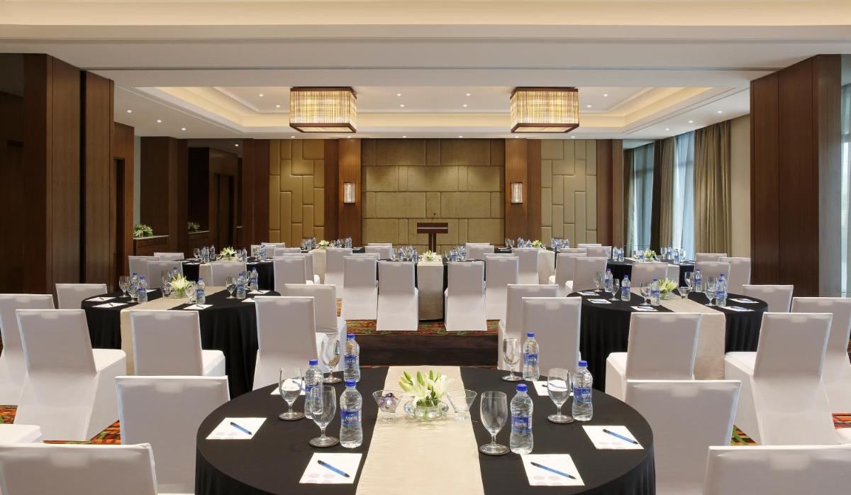 a conference room with tables and white chairs at Novotel Lucknow Gomti Nagar in Lucknow