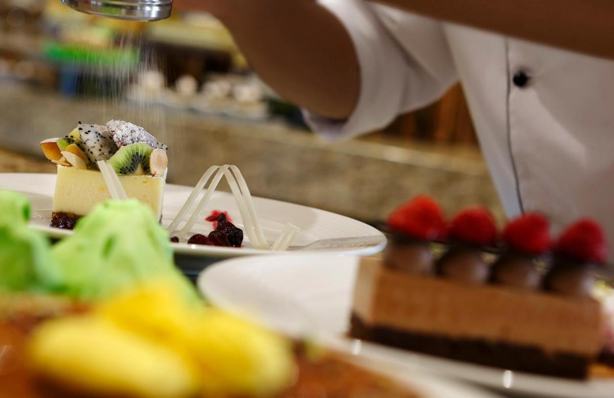 a person cutting a piece of cake on a plate at Novotel Lucknow Gomti Nagar in Lucknow