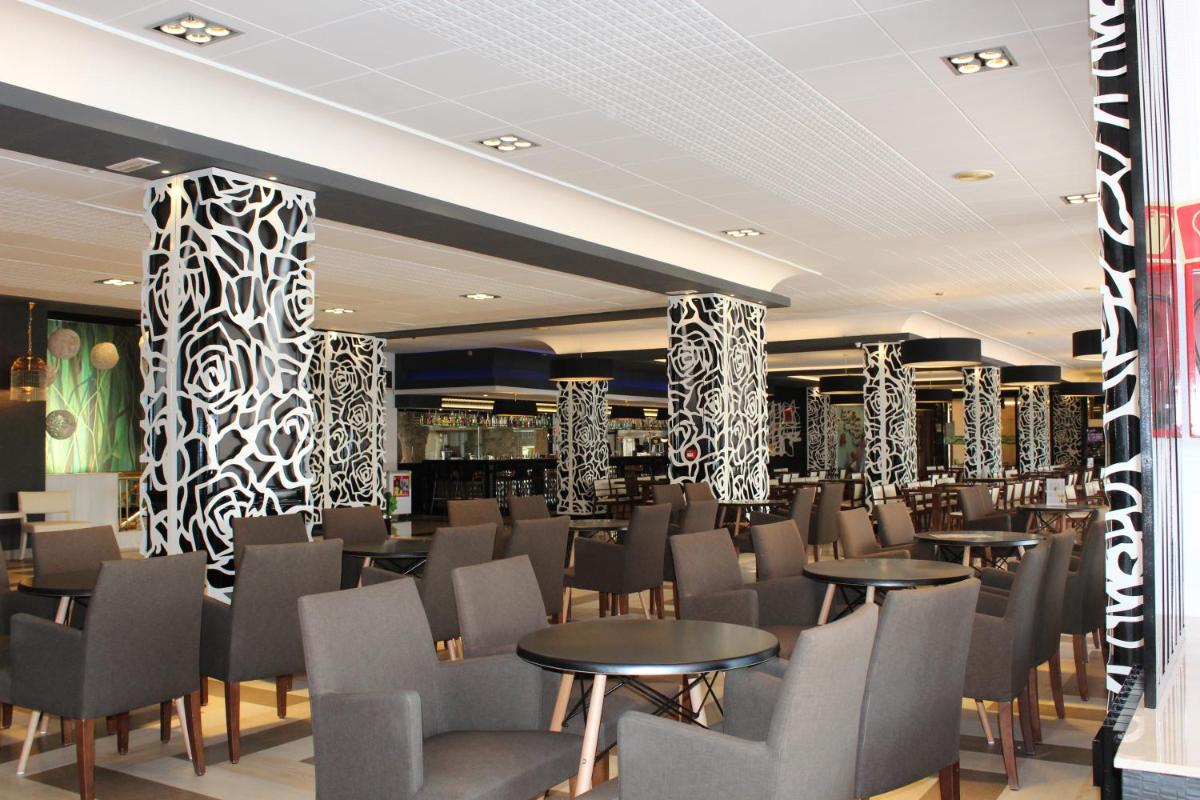 un restaurante con mesas, sillas y columnas en Evenia Olympic Resort, en Lloret de Mar