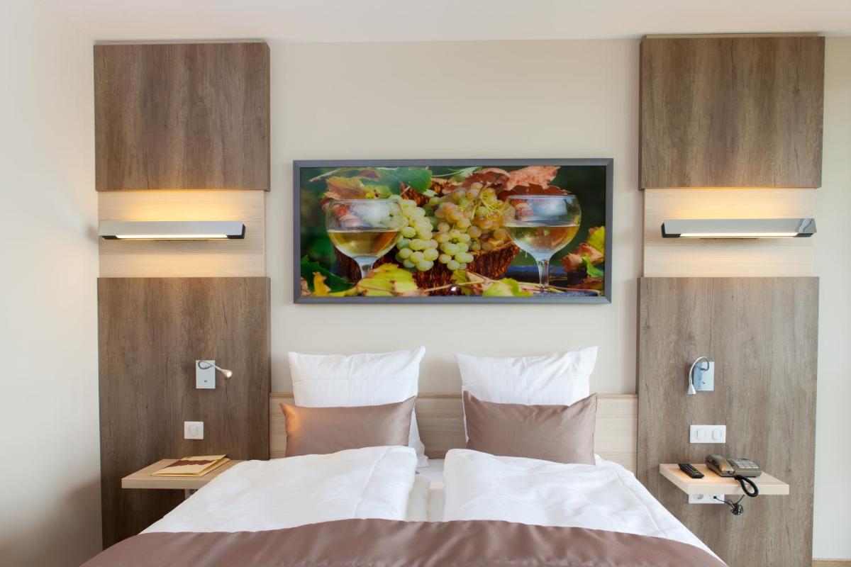 une chambre avec un lit et un tableau au mur dans l'établissement Hotel Restaurant Le Cleebourg, à Rott