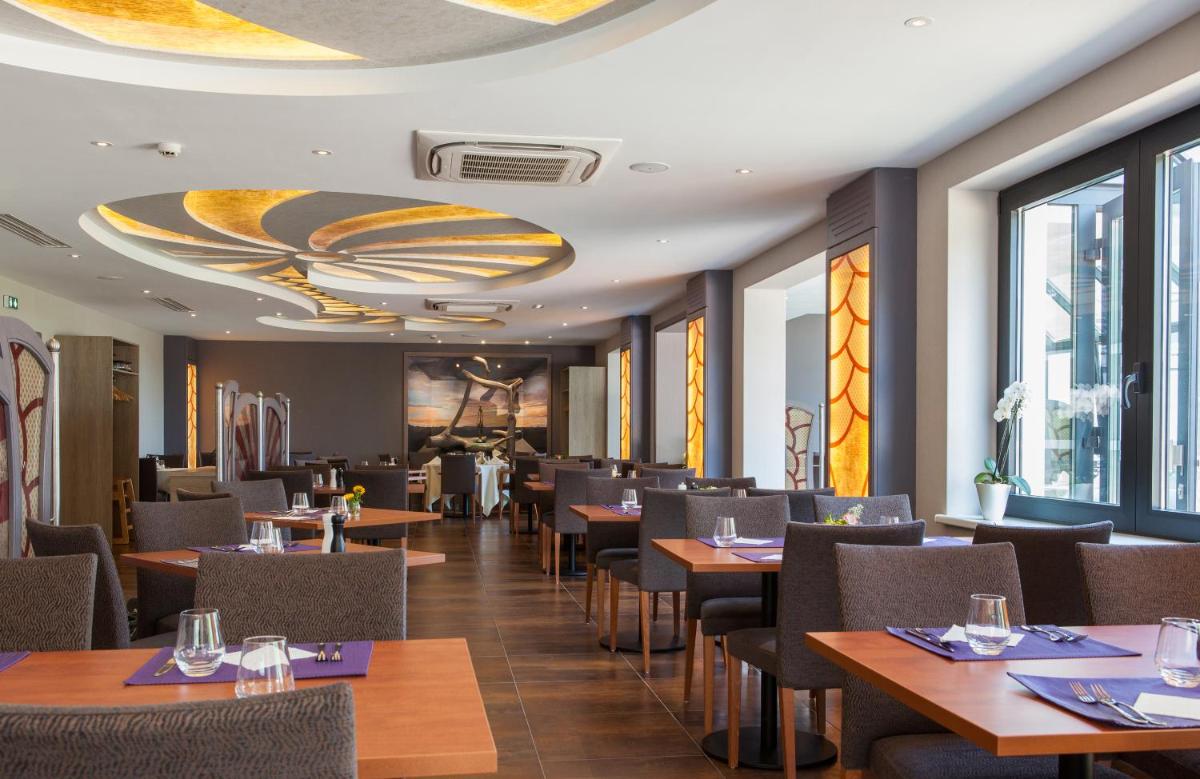 une salle à manger avec tables, chaises et fenêtres dans l'établissement Hotel Restaurant Le Cleebourg, à Rott