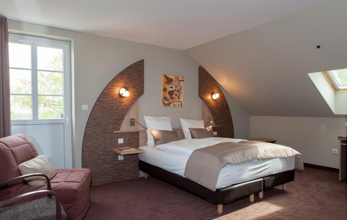 une chambre avec un grand lit et une chaise dans l'établissement Hotel Restaurant Le Cleebourg, à Rott