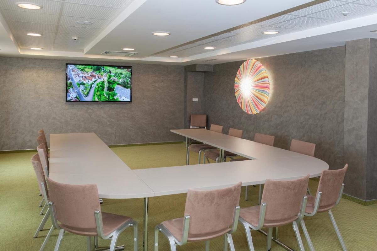 une salle de conférence avec une table, des chaises et une télévision dans l'établissement Hotel Restaurant Le Cleebourg, à Rott
