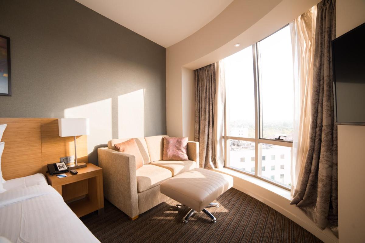 a hotel room with a chair and a window at Novotel Lucknow Gomti Nagar in Lucknow