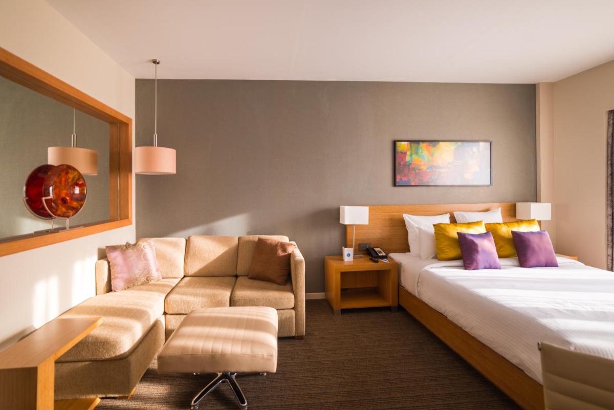 a hotel room with a bed and a chair at Novotel Lucknow Gomti Nagar in Lucknow