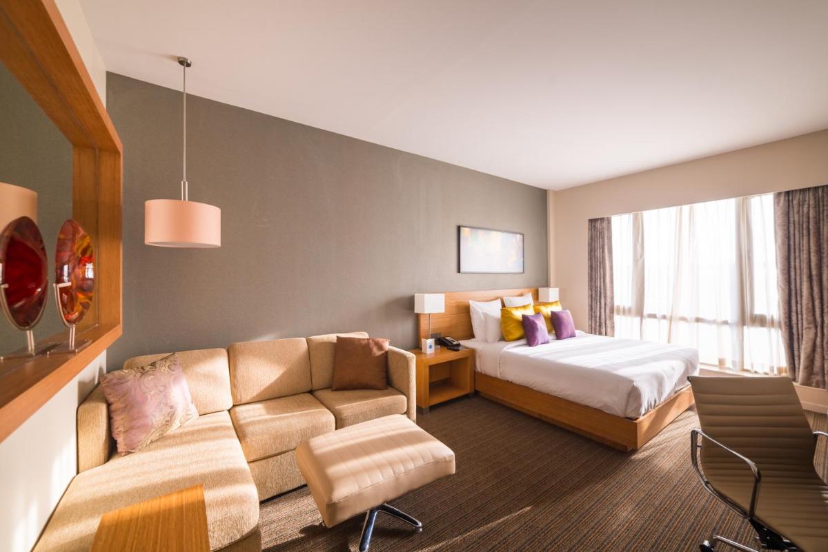 a hotel room with a bed and a couch at Novotel Lucknow Gomti Nagar in Lucknow
